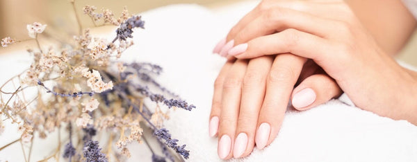 Hands with soft pink almond nails resting on a white towel beside dried lavender