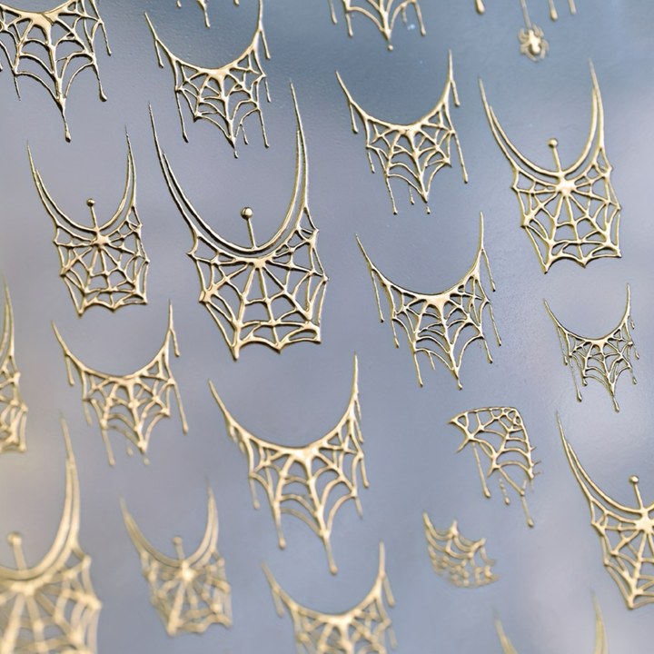 Spider web gold nail art sticker for French, close-up of crescent webs with hanging strands
