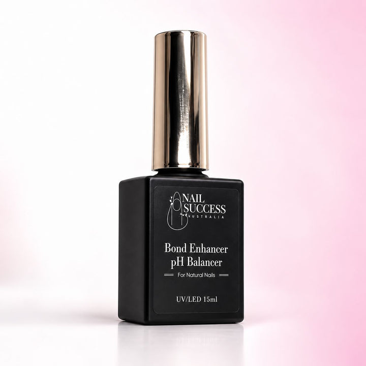 Nail Success Australia Bond Enhancer pH Balancer 15ml in a black bottle with a gold cap on a soft pink background