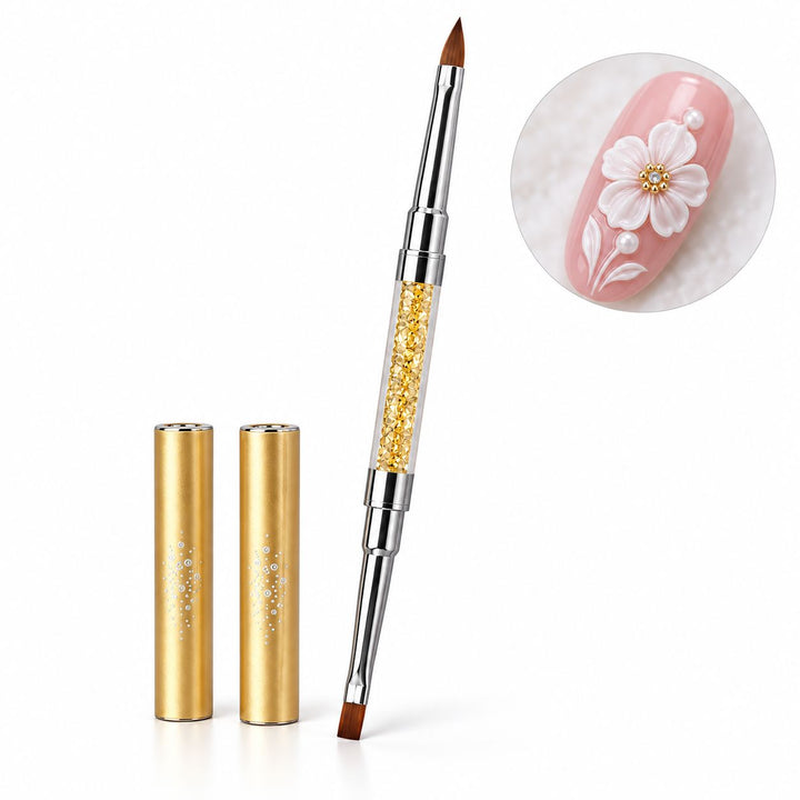 Gold double-ended nail art brush with pointed and flat tips, crystal-filled handle and two protective caps, shown with white 3D floral nail art.