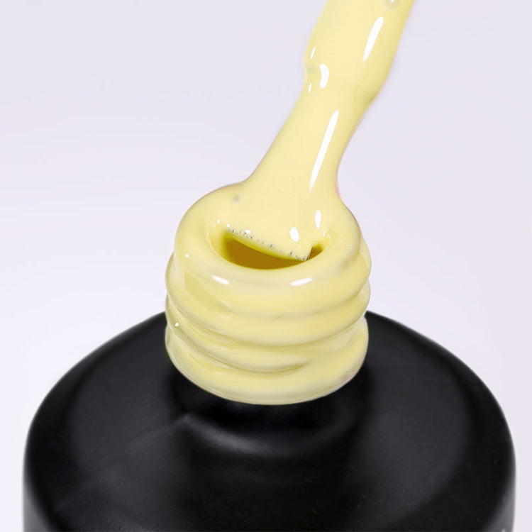 Nail Success Australia gel polish C073 in a soft pastel butter yellow, a close-up of the brush lifting from the bottle neck showing the creamy colour