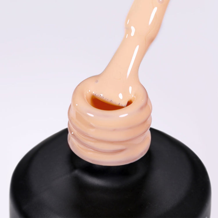 Nail Success Australia gel polish C075 in a soft pastel peach, a close-up of the brush lifting from the bottle neck showing the creamy colour