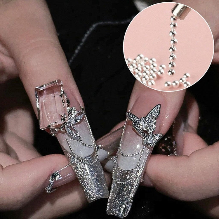 Silver caviar bead nail art with glitter French tips, butterfly charms and rhinestone manicure design sample