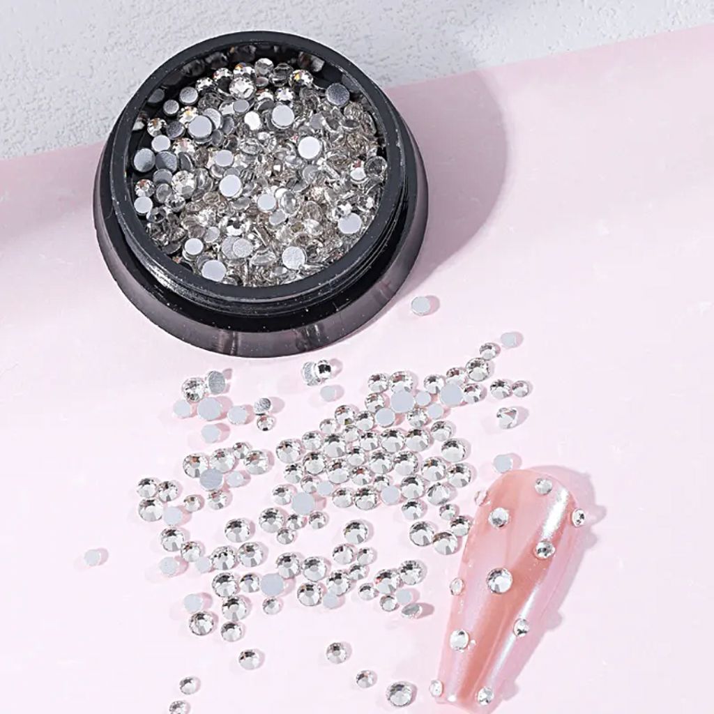 NSI Australia clear nail art rhinestones — mixed-size flatback crystals in jar with sample pink nail tip