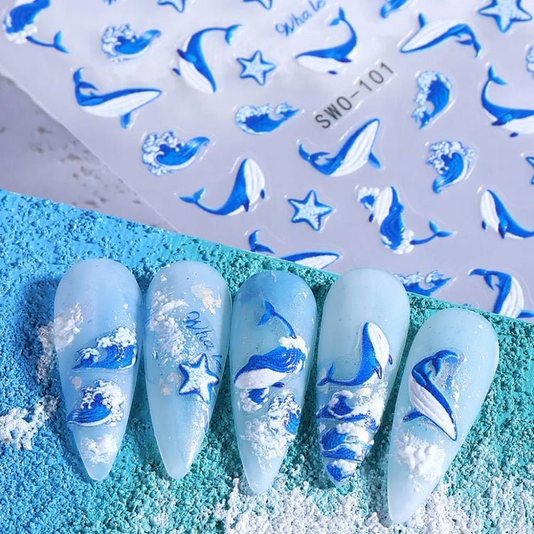 Nail Success Australia SWO-101 blue whale nail art stickers shown on light blue ocean-themed sample nails with waves, starfish and whale designs