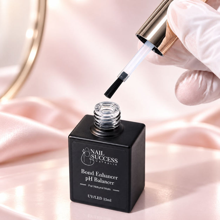 Brush lifting out of an open bottle of Bond Enhancer pH Balancer, ready for a thin layer on the natural nail