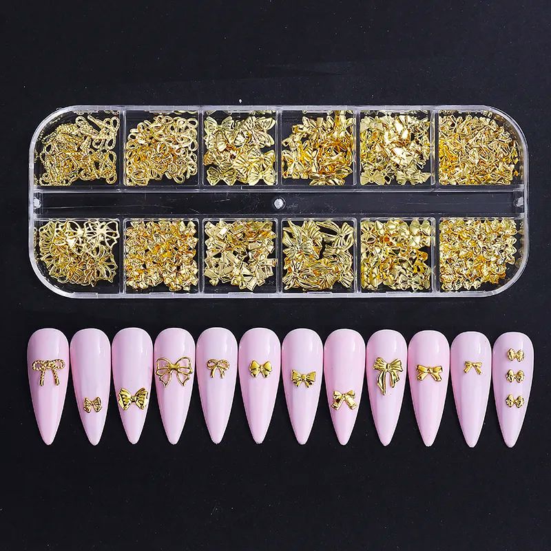 Gold nail art charms mix in clear compartment tray with pink nail tip display, 3D metal bow and ribbon decorations
