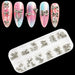 Silver nail art charms set in clear compartment tray with 3D metal bow and ribbon decorations, shown on pink nail tips