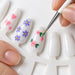 Fine detail brush painting purple flowers and pink roses on white nail tips with the 20 piece nail art set