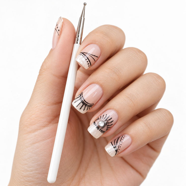 Nail art liner brush held beside a hand with fine black line work and rhinestone accent nails