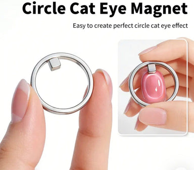 Silver ring-shaped cat eye magnet nail tool shown between fingers with an example of a circular cat eye effect on a pink nail