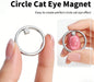 Silver ring-shaped cat eye magnet nail tool shown between fingers with an example of a circular cat eye effect on a pink nail