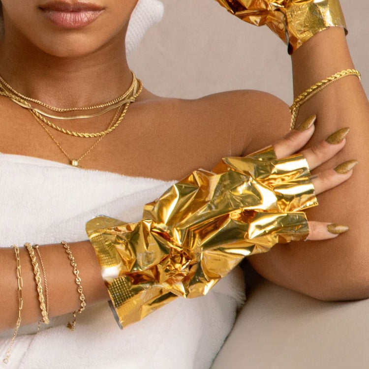 Close-up lifestyle image of VOESH Imperial Gold Collagen Gloves hand mask in use with gold manicure and spa-style styling
