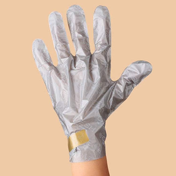 Hand wearing Voesh collagen glove hand mask with argan oil and floral extracts