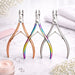 Three cuticle nippers in rose gold, rainbow and silver finishes displayed on a manicure table with towel, flowers and cream jar