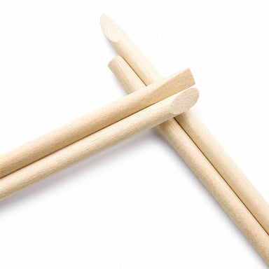 Close-up of wooden cuticle pusher sticks crossed together, highlighting the large angled flat ends and smooth natural wood finish