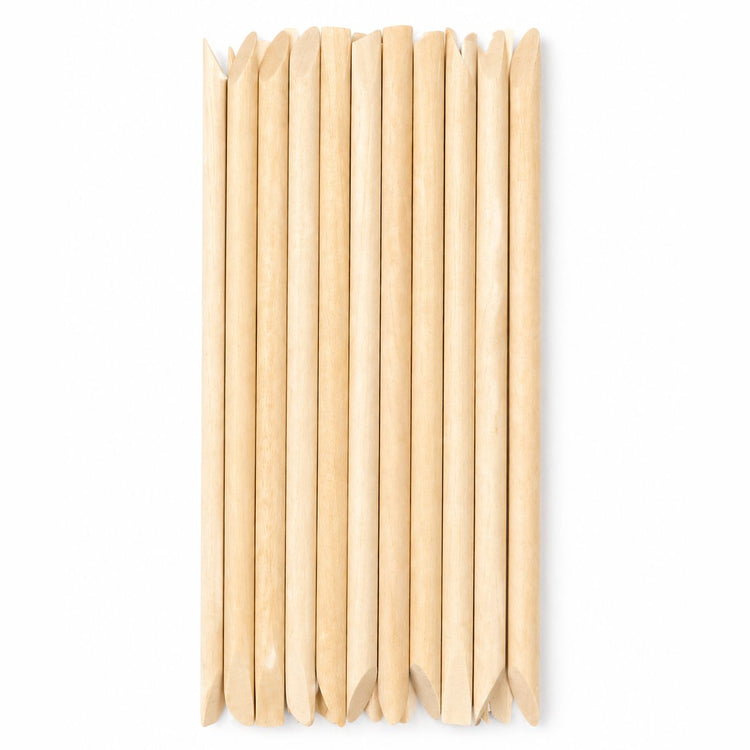 Bundle of wooden cuticle pusher sticks with large angled flat ends and pointed tips arranged on a white background