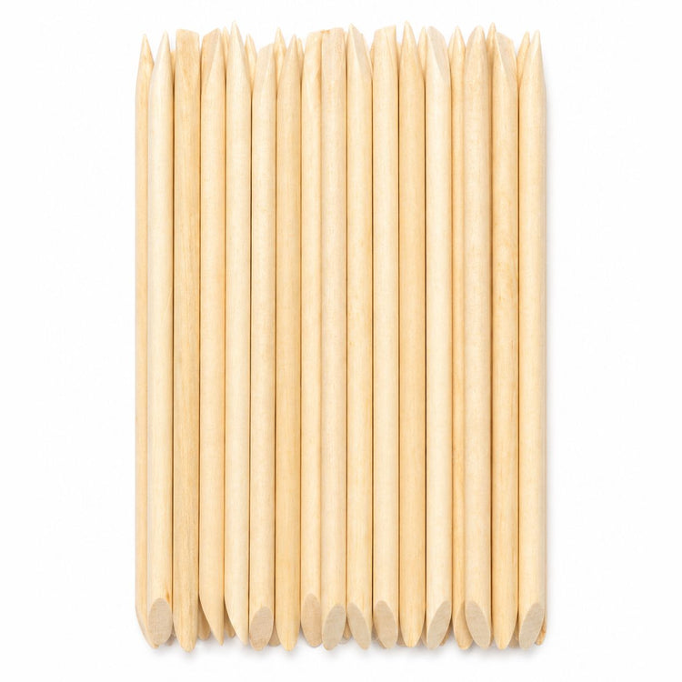 Bundle of wooden cuticle pusher sticks with large angled flat ends and pointed tips arranged on a white background