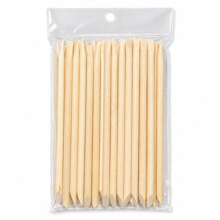 Pack of wooden cuticle pusher sticks with large angled flat ends and pointed tips in clear hanging plastic bag packaging