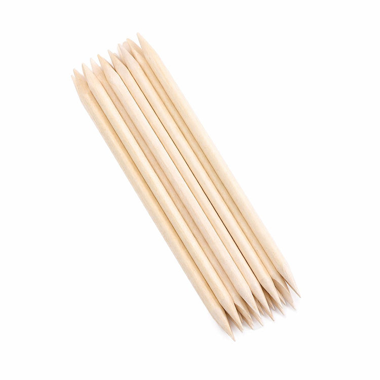 Bundle of wooden cuticle pusher sticks stacked diagonally, showing pointed tips and angled flat ends on a light gray background