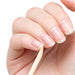 Close-up of natural nails with a wooden cuticle pusher stick being used for gentle nail edge and cuticle cleaning