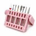 Eight-piece ceramic and diamond nail drill bit set in assorted shapes, displayed in an angled pink storage stand.
