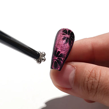 Black double-ended magnetic nail art stick with flower magnet tip creating pink cat eye gel polish effects and floral magnetic nail designs