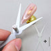 Double-ended scissor-shaped cat eye nail magnet tool creating cat eye effect on pink gel nail tip