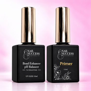 Nail Success Australia Bond Enhancer pH Balancer and Nail Primer duo, two 15ml black bottles with gold caps on a soft pink background