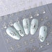 Silver flower outline nail art stickers with floral petal decals shown on light blue manicure