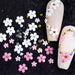 White & pink 3D flower nail art charms — mixed-size daisies with pearls and gold beads, shown on nude tips for DIY gel or acrylic nails