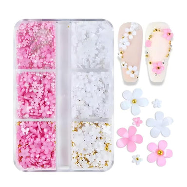 White & pink 3D flower nail art charms set — assorted daisies with pearls and gold beads in 6-grid box, shown on sample tips for DIY gel or acrylic nails