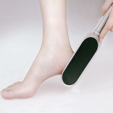 White-handled double-sided foot file used on heel — black coarse grit for callus removal