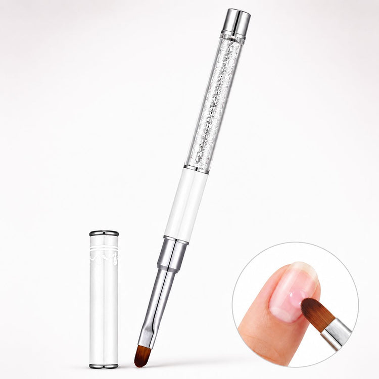 White gel nail brush with oval bristles, a crystal-filled handle and matching cap, shown applying pink gel to a natural nail.
