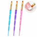Three flat gel nail brushes with blue, purple and pink glitter handles and gold ferrules, shown painting a white French tip.

