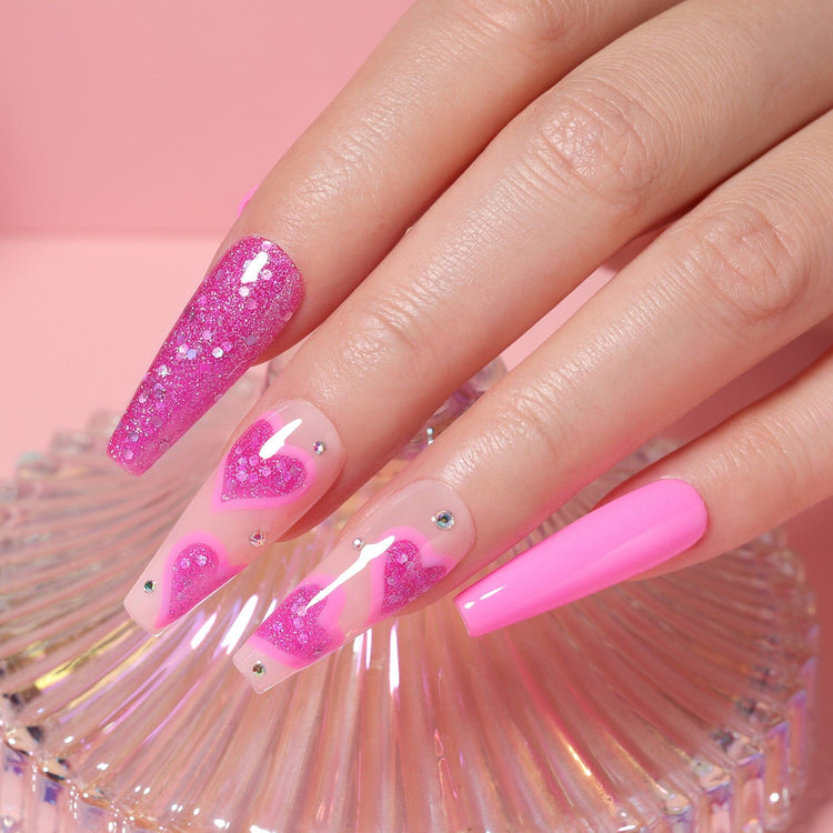 Hot pink gel polish manicure with glitter hearts and rhinestones on long coffin nails, glossy finish