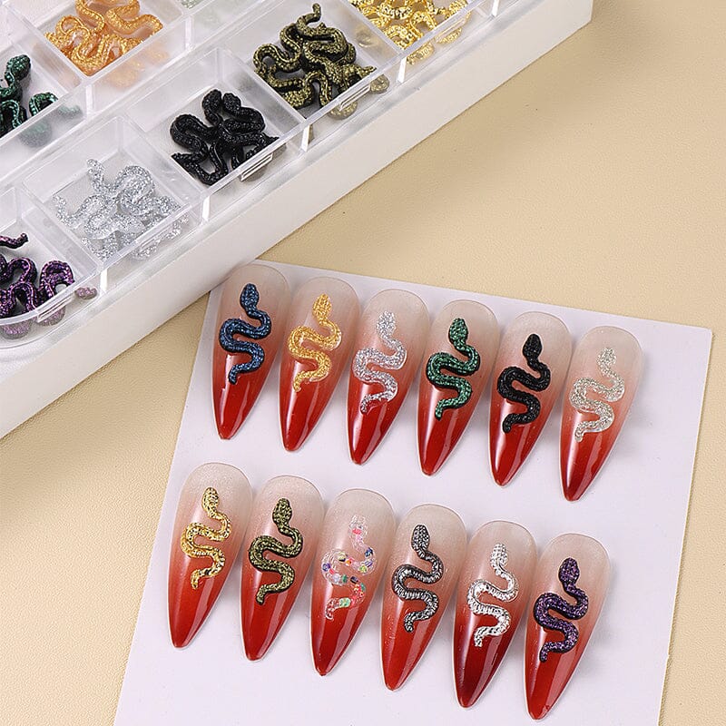 3D snake nail charms set, 12 colors, shown on red stiletto tips — sparkly rhinestone decals for Halloween gel or acrylic nails