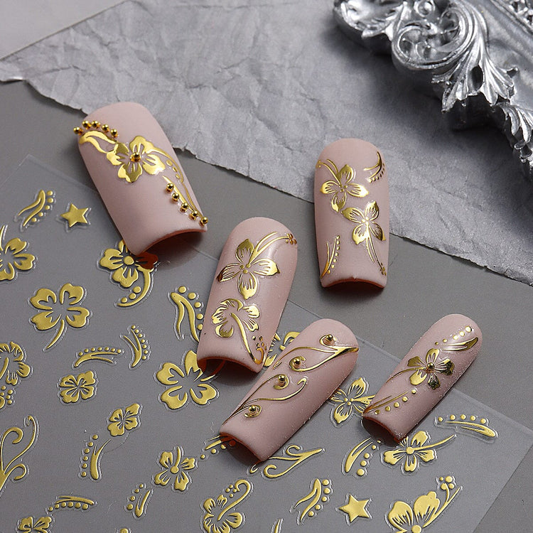 Nail Success Australia gold hibiscus flower nail stickers shown with nude floral manicure designs and gold accents