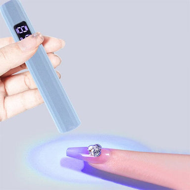 Blue USB rechargeable LED nail torch flash curing a gel tip with a rhinestone accent