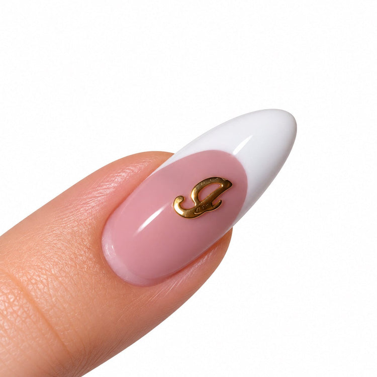 Gold script letter I nail art charm on a pink French tip almond nail