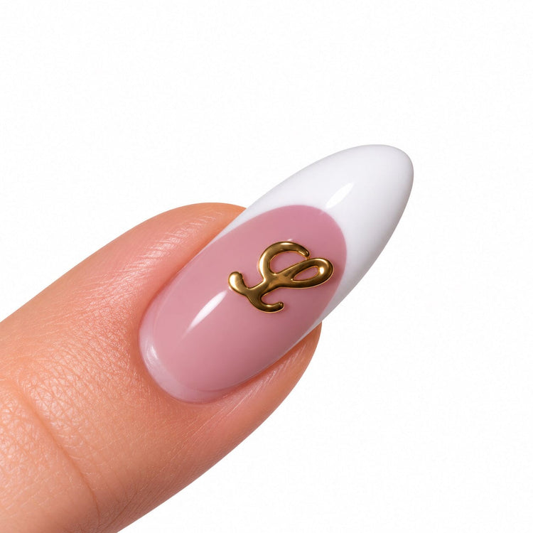 Gold script letter L nail art charm on a pink French tip almond nail