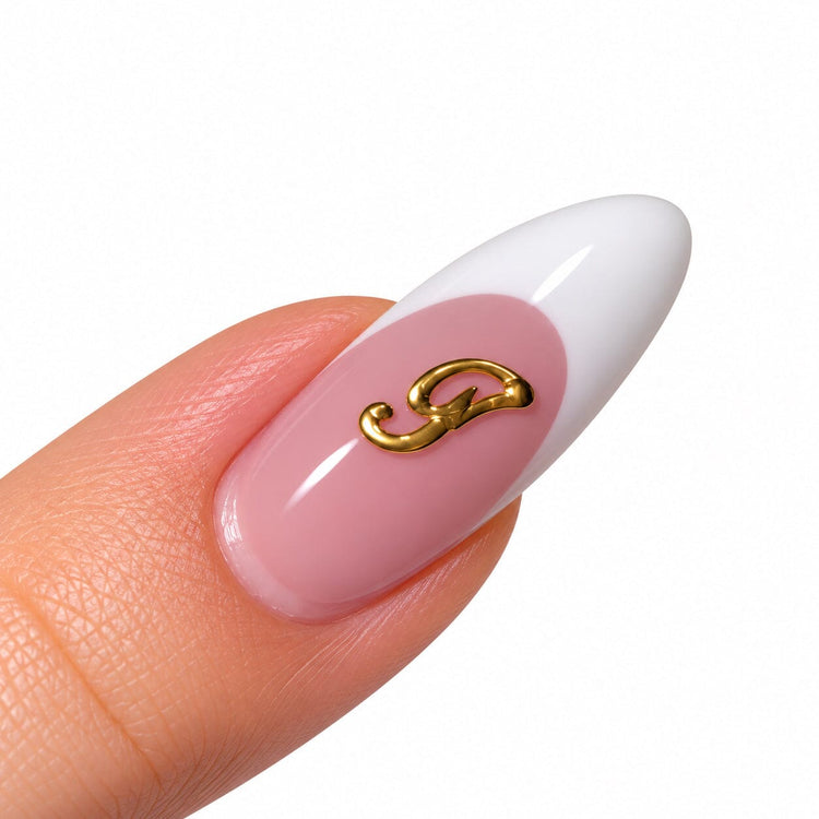 Gold script letter T nail art charm on a pink French tip almond nail