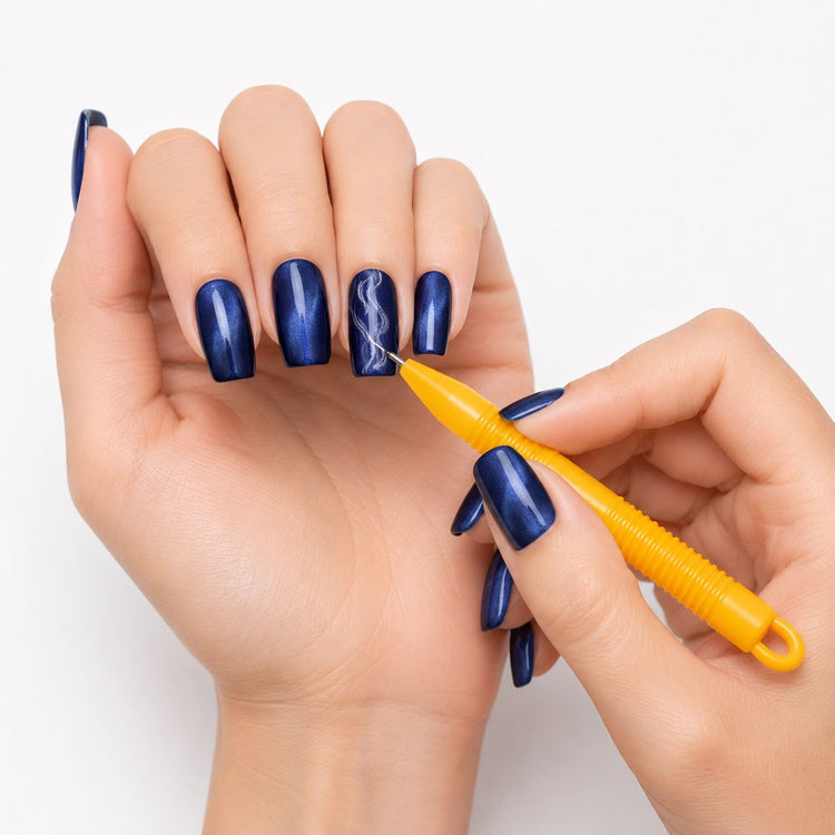 Orange cat-eye magnet pen creating fine swirl patterns in blue magnetic gel polish on manicured nails