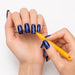 Orange cat-eye magnet pen creating fine swirl patterns in blue magnetic gel polish on manicured nails