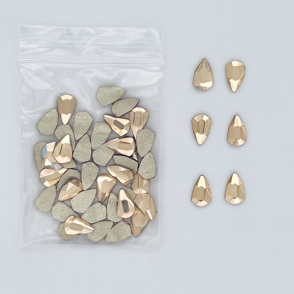 NSI Australia Luxury Rhinestones Series 6 — R08 teardrop-shield shape, champagne-gold faceted flatback nail art crystals, bulk pack with a few pieces shown beside the bag
