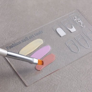 Clear nail art design palette with nail shape guides, pastel gel polish swatches and brush for colour mixing