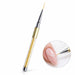 Gold 20 mm nail art liner brush with crystal-filled handle, shown painting fine white curves on a nude pink nail.