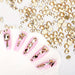 Gold nail art rhinestones — mixed-size flatback crystals shown on pink nail tips, manicure design examples — NSI Australia