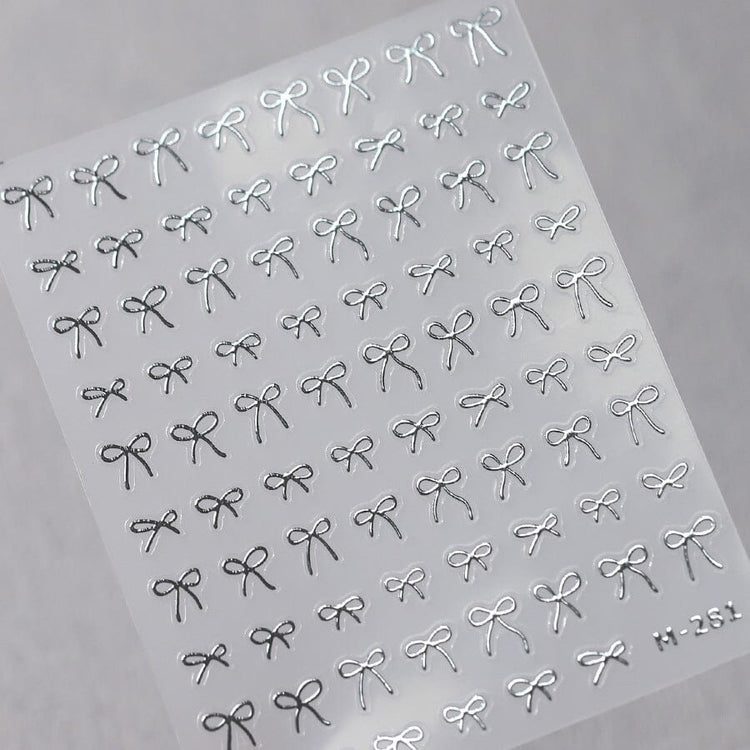 Silver bow nail art stickers sheet with delicate metallic ribbon designs for elegant salon manicure decorations