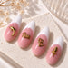 Gold dolphin, “Love”, double-heart and rose nail charms displayed on pink and white French almond nail tips.